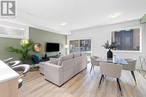 Toronto (Dufferin Grove) fourplex for rent - A modern living room with a grey sofa, a glass table, and a TV mounted on the wall.