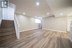 Brantford apartment for rent - A spacious room with wooden flooring and a staircase leading to another level.