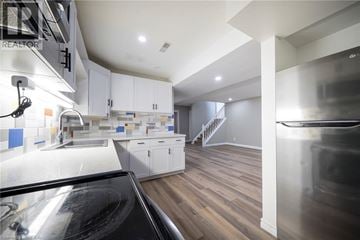 Brantford apartment for rent - A modern kitchen with white cabinets and a wooden floor.