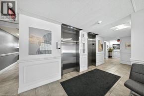Kitchener condo for rent - A hallway with a black carpet and a grey chair.