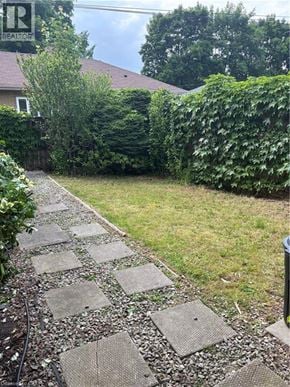Stoney Creek apartment for rent - A stone pathway leads through a lush green garden.