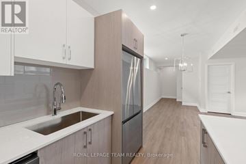 Ottawa multi-family for rent - A modern kitchen with white cabinets and a stainless steel refrigerator.