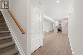 Ottawa multi-family for rent - A hallway with a staircase and a door leading to a kitchen area.