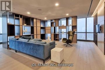 Toronto (Bay Street Corridor) condo for rent - A modern living room with a blue velvet sofa and a wooden floor.