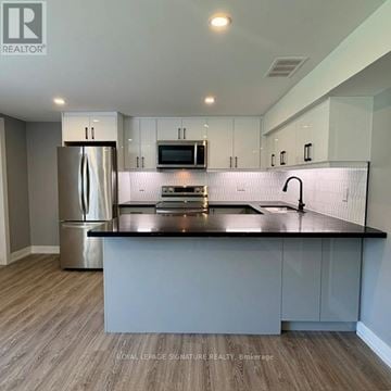 Toronto (Victoria Village) apartment for rent - A modern kitchen with a stainless steel refrigerator and a black countertop.