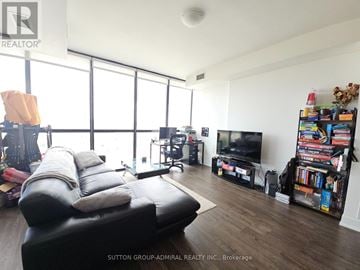 Vaughan (Concord) condo for rent - A living room with a black leather sofa and a television.
