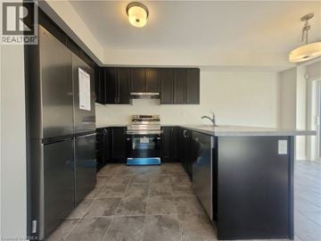 Brantford townhouse for rent - A kitchen with black cabinets and a tiled floor.