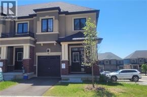 Brantford townhouse for rent - A large house with a garage and a car parked in front.