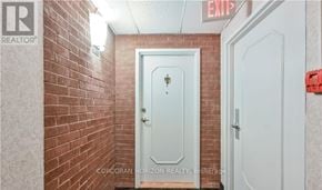 Hamilton (Ainslie Wood) condo for rent - A white door with a cross on it is in a hallway with a red exit sign above it.