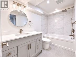 Binbrook apartment for rent - A bathroom with a marble wall and a round mirror above a sink.