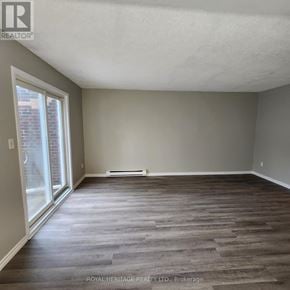 Oshawa (Pinecrest) townhouse for rent - A room with wooden flooring and a sliding glass door.