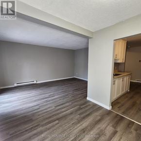 Oshawa (Pinecrest) townhouse for rent - A room with wooden flooring and a kitchenette in the corner.