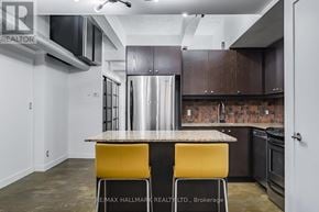 Toronto (South Riverdale) condo for rent - A kitchen with a stainless steel refrigerator, a countertop, and yellow chairs.