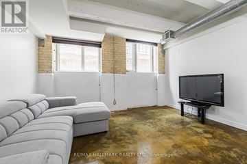 Toronto (South Riverdale) condo for rent - A living room with a grey sofa and a television.