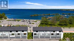 Orillia townhouse for rent - A view of a parking lot with a building in the background and a body of water in the distance.