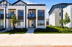 Orillia townhouse for rent - A modern two-story building with balconies and a small garden in front.