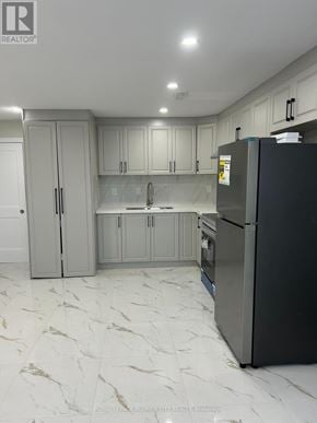 Brantford apartment for rent - A kitchen with a black fridge and marble flooring.