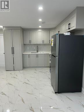 Brantford apartment for rent - A black refrigerator in a kitchen with marble flooring and white cabinets.
