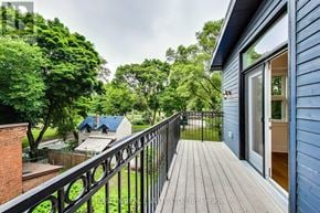 Toronto (Dufferin Grove) fourplex for rent - A balcony with a black railing overlooks a lush green yard.