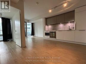 Toronto (Church-Yonge Corridor) condo for rent - A spacious, empty room with a kitchen area in the background.