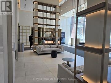 Toronto (Newtonbrook East) condo for rent - A modern living room with a large couch and a person standing in the background.