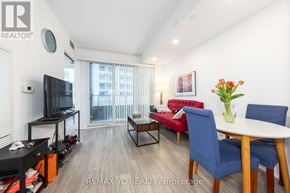Toronto (Niagara) condo for rent - A living room with a red sofa, a blue chair, a white table, and a television.