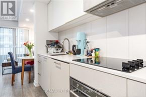 Toronto (Niagara) condo for rent - A kitchen with white cabinets and a blue chair.