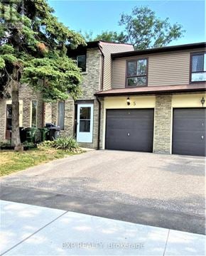 Toronto (Agincourt North) townhouse for rent - A house with a driveway and garage doors.