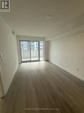 Pickering (Bay Ridges) condo for rent - A room with wooden flooring and a sliding glass door leading to a balcony.
