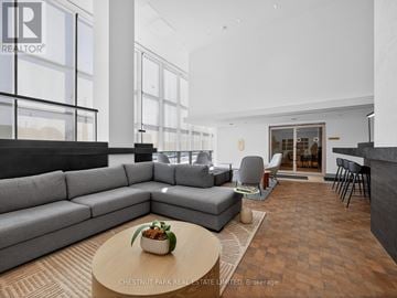 Toronto (Greenwood-Coxwell) condo for rent - A modern living room with a grey sofa and a coffee table with a plant on it.