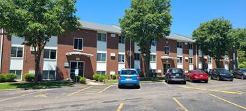 Dayton apartment for rent - A parking lot with cars parked in front of a brick building.