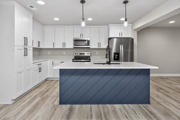 Urbandale apartment for rent - A modern kitchen with white cabinets and a dark blue island.