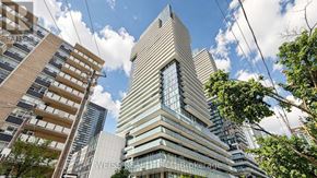 Toronto (Mount Pleasant West) condo for rent - A tall building with a glass facade stands in the middle of a cityscape.