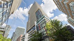 Toronto (Mount Pleasant West) condo for rent - A tall building with a glass facade stands in the middle of a cityscape.