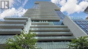 Toronto (Mount Pleasant West) condo for rent - A tall building with a glass facade and a tree in front of it.