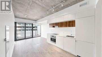 Toronto (Mount Pleasant West) condo for rent - A modern kitchen with white cabinets and a wooden backsplash.