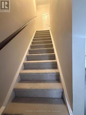 Cambridge townhouse for rent - A staircase with a carpeted runner and a wooden handrail.