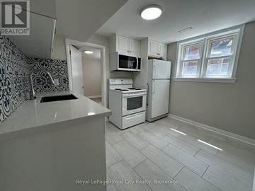 Guelph (Downtown) fourplex for rent - A kitchen with white appliances and a patterned backsplash.