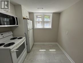 Guelph (Downtown) fourplex for rent - A white kitchen with a stove, microwave, and refrigerator.