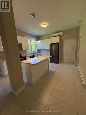Ottawa multi-family for rent - A kitchen with white cabinets and a black fridge.