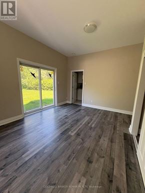 Ottawa multi-family for rent - A room with wooden flooring and a sliding glass door leading to a green outdoor area.