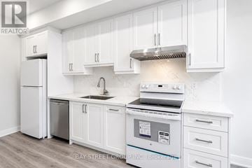Toronto (Kensington-Chinatown) multi-family for rent - A white kitchen with a stove top oven and a refrigerator.