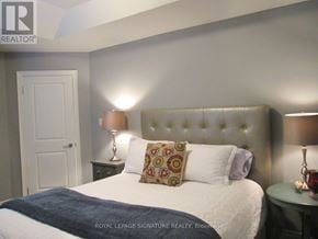 Toronto (Mimico) apartment for rent - A bedroom with a bed, two lamps, and a wall-mounted headboard.