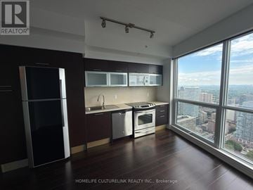 Toronto (Bay Street Corridor) condo for rent - A modern kitchen with dark wood floors and stainless steel appliances.
