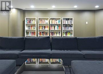 Toronto (Little Portugal) condo for rent - A living room with a grey sofa and a coffee table in front of a bookshelf.