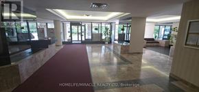Toronto (Mount Olive-Silverstone-Jamestown) condo for rent - The lobby of a building with a red carpet and a sign that reads "HOMELIFE/MIRACLE REALTY LTD, Brokerage".