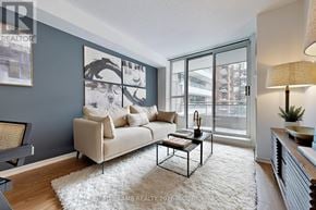 Toronto (Mount Pleasant West) condo for rent - A living room with a beige couch, a coffee table, and a large window.