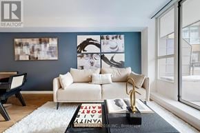 Toronto (Mount Pleasant West) condo for rent - A living room with a white couch and a coffee table with a book on it.