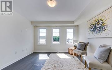Oakville (Go Glenorchy) townhouse for rent - A living room with a grey couch, a white rug, and a painting on the wall.