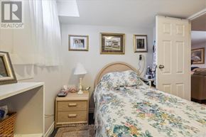 Hamilton (Huntington) apartment for rent - A bedroom with a floral bedspread and a white bedside table with a lamp on it.